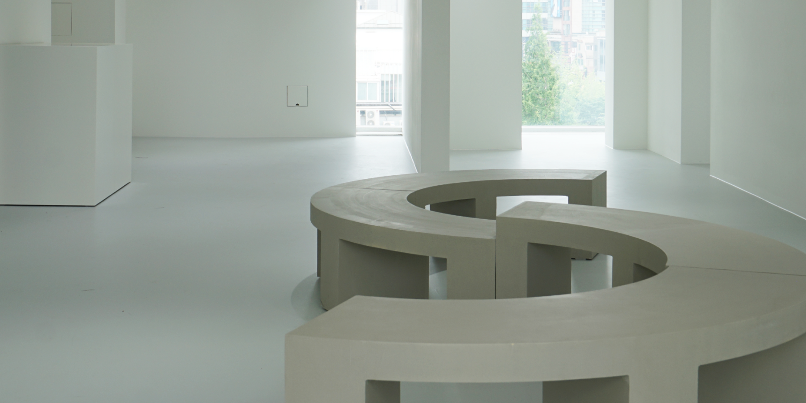 곡선형 콘크리트 벤치가 있는 미니멀 전시 공간